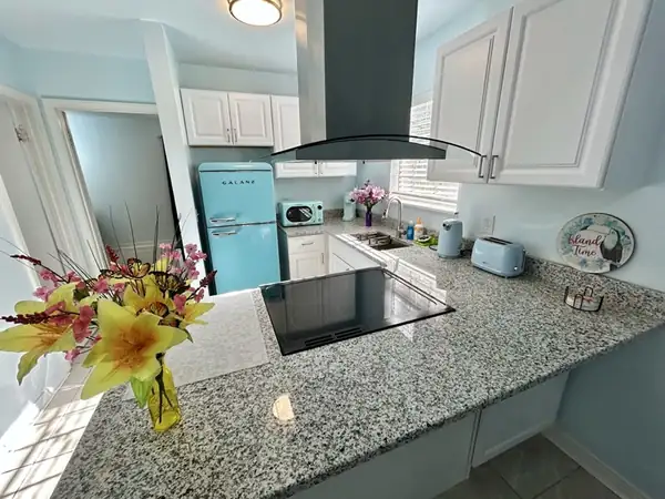 Kitchen with a mint retro refrigerator, granite peninsula and island cooktop