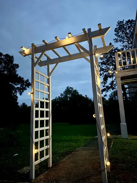 White arbour lit at dusk