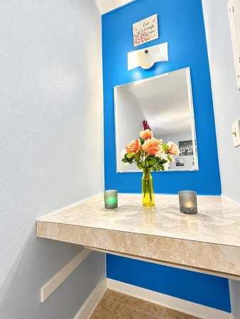 Vanity nook with a mirror, flowers and candles against a blue wall