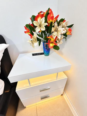 Nightstand with flowers and soft under-light beside the bed
