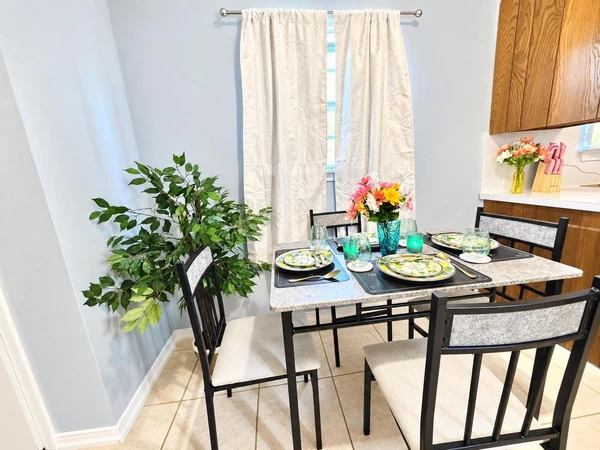 Dining table for four by the window, set with plates and flowers