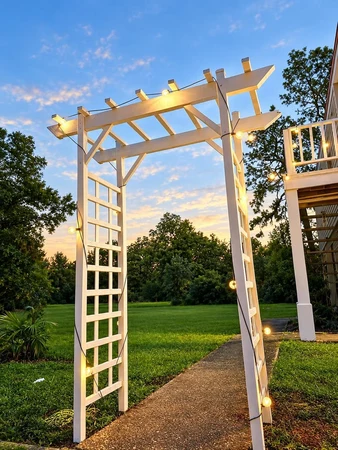 White arbor lit with string lights at dusk