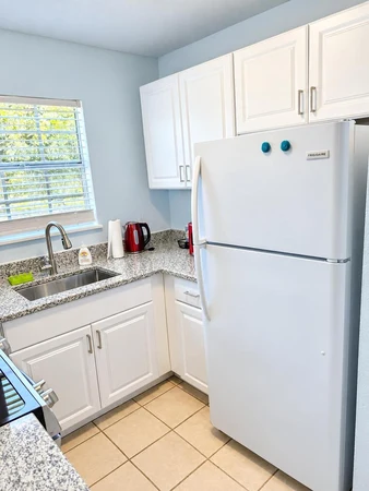 Kitchen with a white fridge, granite counters and a sink under the window