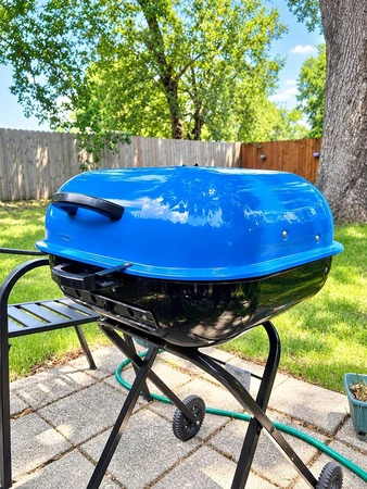 Blue charcoal grill on the backyard patio