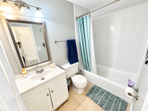 Bathroom with a tub-shower, teal shower curtain and bath mat