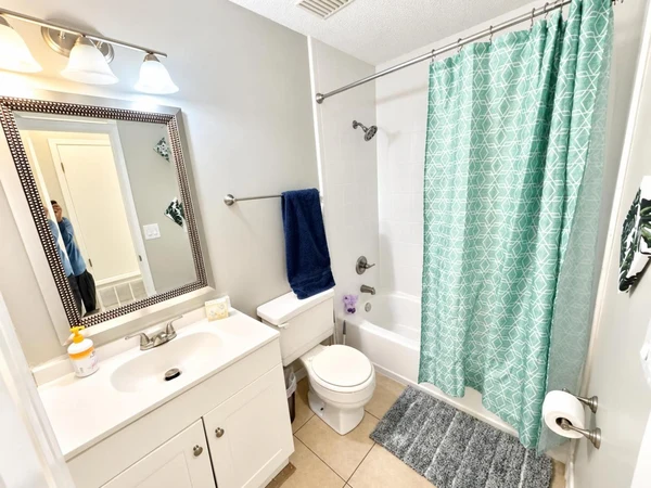 Bathroom vanity with a framed mirror beside the tub-shower