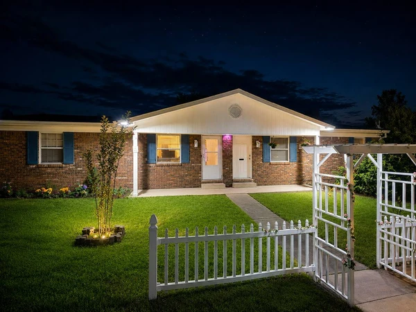Front of the duplex at night with the lit garden and white arbor