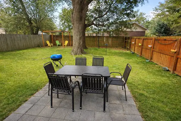Fenced backyard with a patio dining set under a large oak
