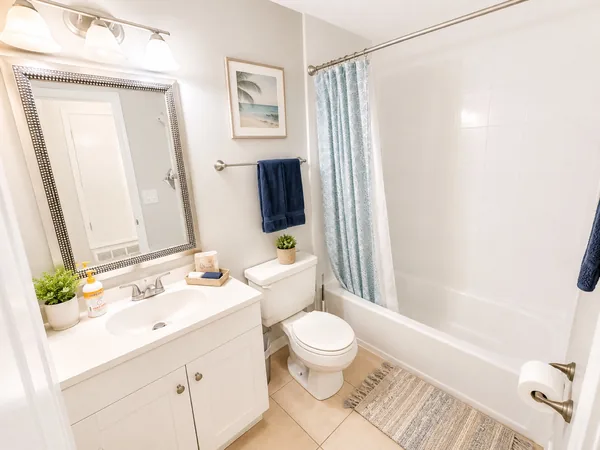Bathroom with a tub-shower, vanity and framed mirror