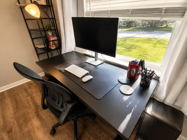 Desk workstation with a monitor beside a window over the front lawn